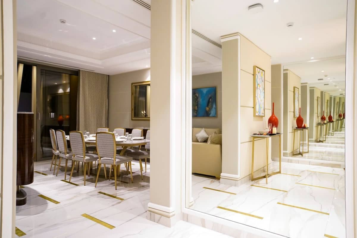 A hotel dining area with a marble floor, gold accents, and a large mirror reflecting the space.