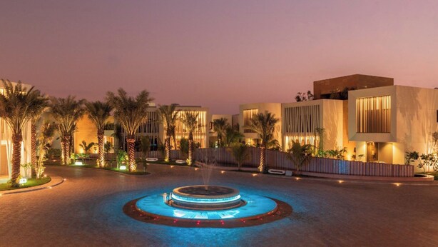 A modern hotel courtyard with a central fountain, palm trees, and contemporary buildings. - Vivienda Hotel Villas Jeddah (Jeddah)