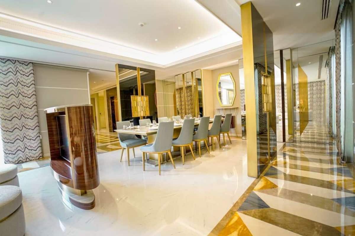 A modern dining area with a long table, multiple chairs, and a decorative column.