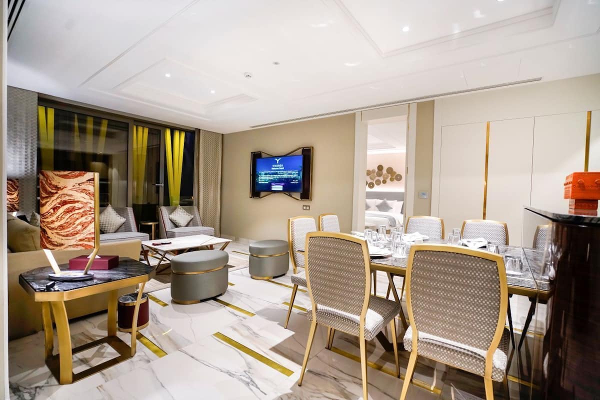 A modern hotel room with a dining area, a TV, and a bed with a view.