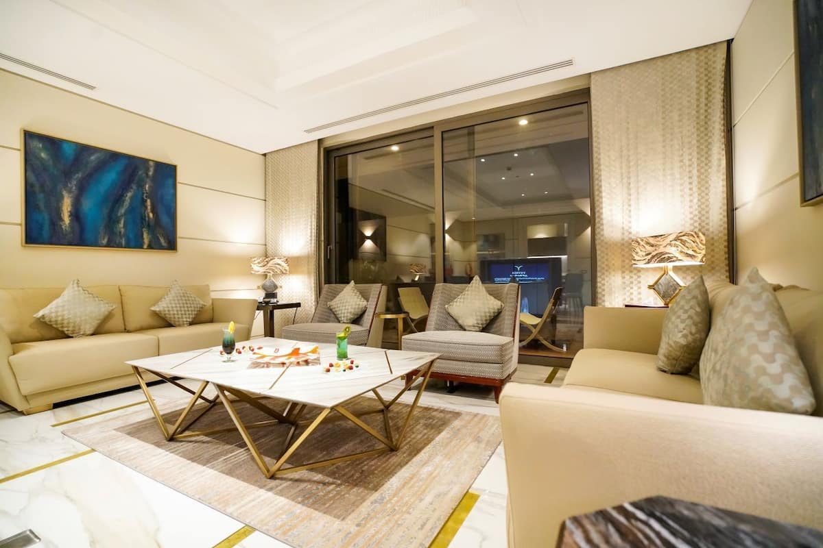 A modern living room with a beige sofa set, a coffee table, and a large abstract painting.