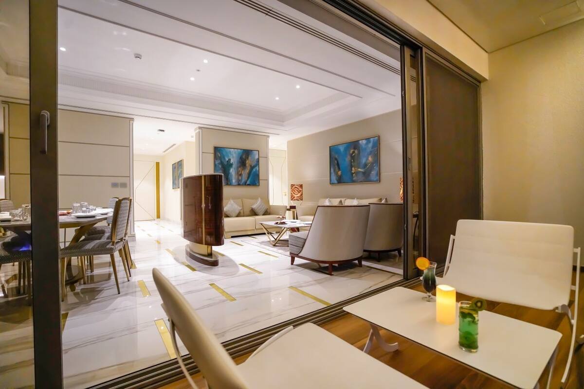 A modern hotel room with a dining area, a sofa set, and artwork on the walls.