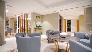 A modern hotel lobby with a round marble table, two armchairs, and a dining area with a glass partition. - Vivienda Hotel Villas Jeddah (Jeddah)