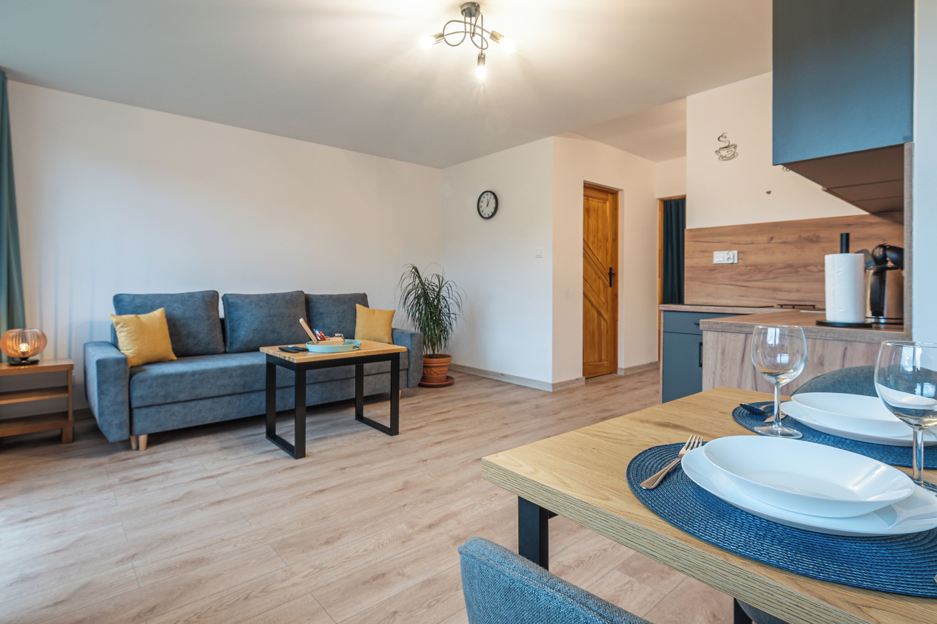 A modern living room with a sofa, coffee table, and dining area set for two.