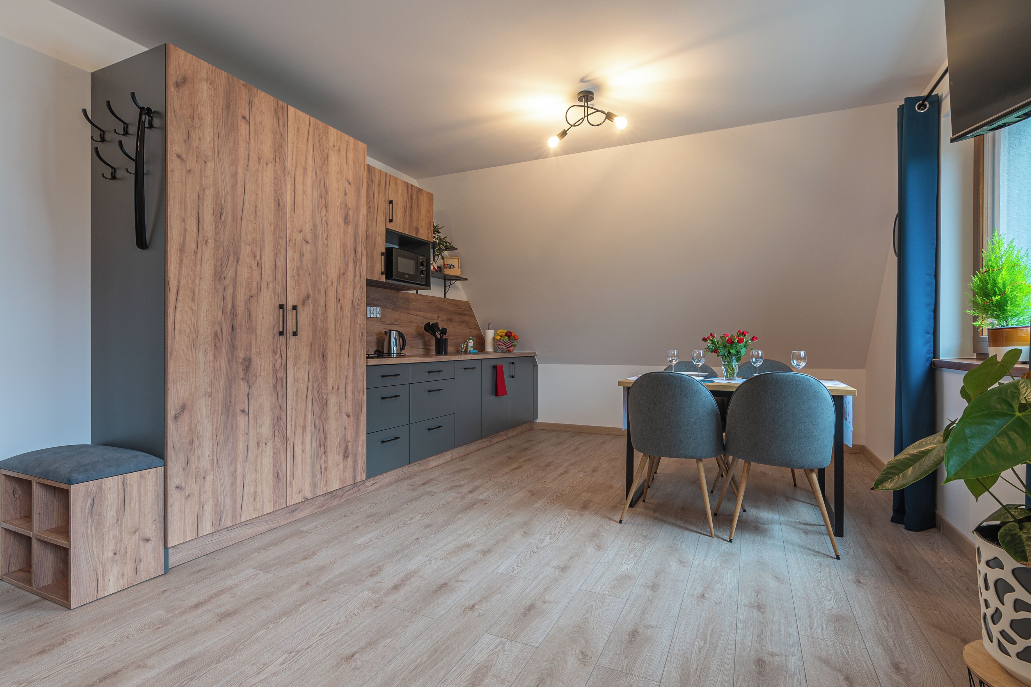 A modern kitchen with wooden cabinets, a dining area with two chairs, and a small seating bench.
