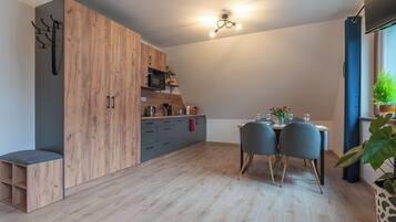 A modern kitchen with wooden cabinets, a dining area with two chairs, and a small seating bench.