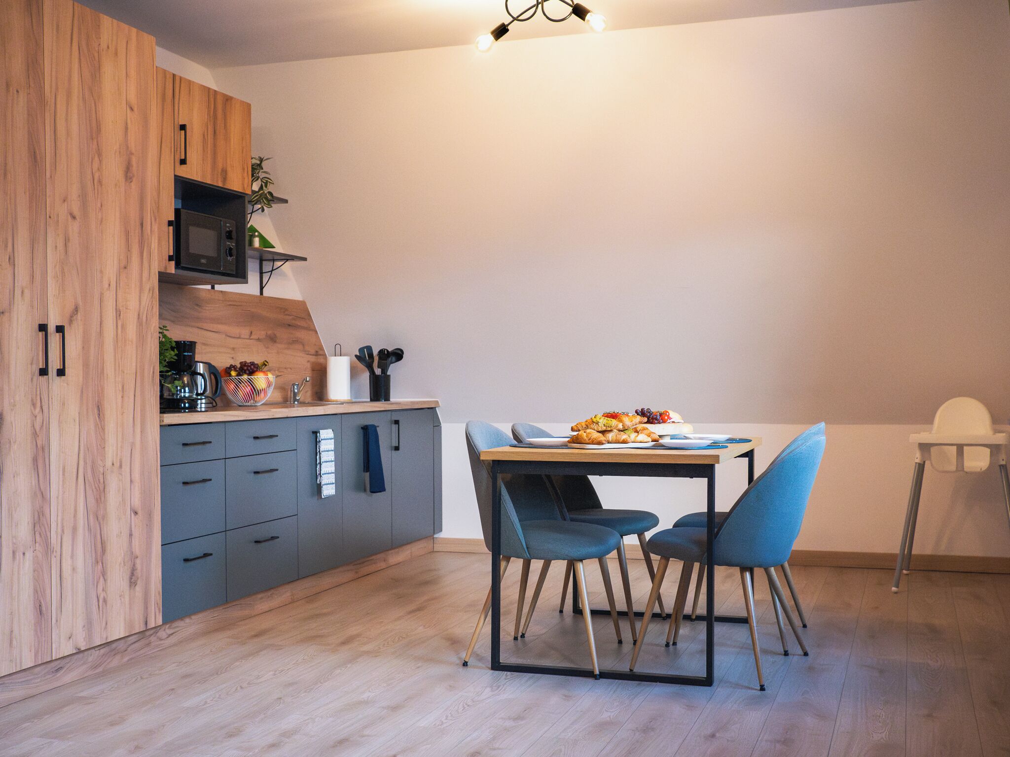 Uma cozinha moderna com armários de madeira, micro-ondas e um espaço de jantar com mesa e cadeiras.