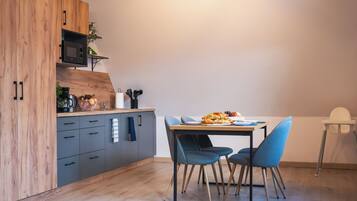 Una cocina moderna con armarios de madera, un microondas y un comedor con mesa y sillas.