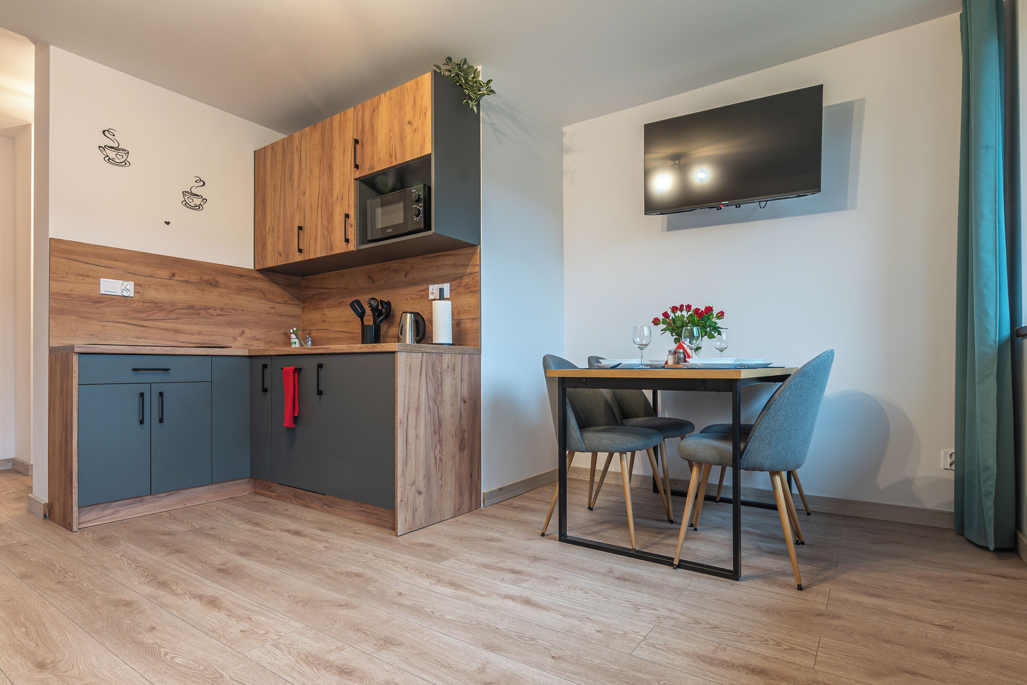 A modern kitchen with wooden cabinets, a microwave, and a dining area with a table and chairs.