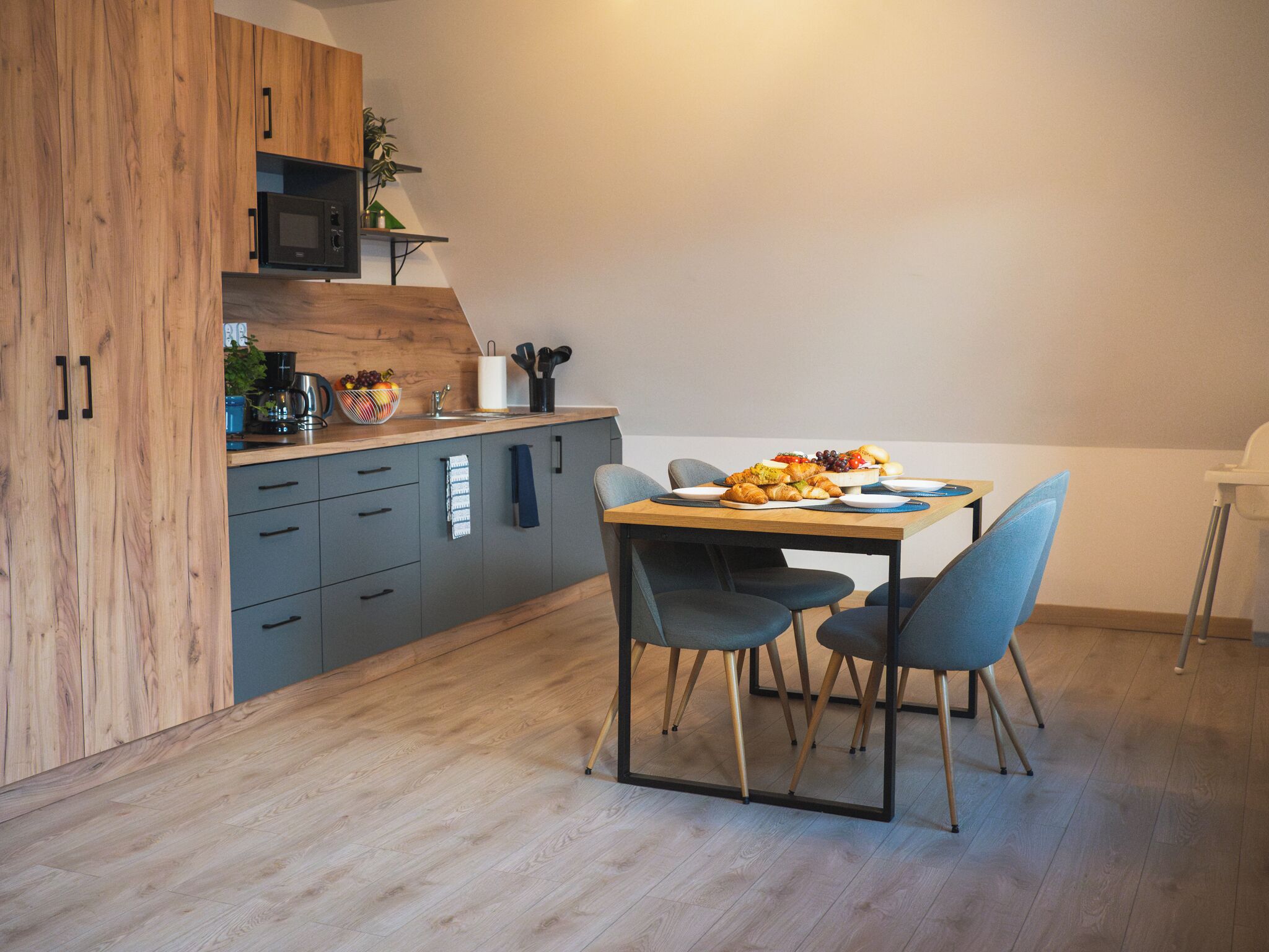 Una cocina moderna con armarios grises, una encimera de madera y una mesa de comedor con sillas.