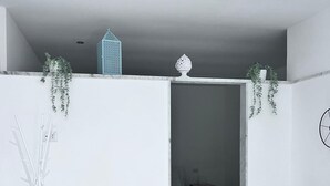 A modern, minimalist bedroom with a bed, two white chairs, a white wardrobe, and a small plant on the ceiling. - 1 Bedroom Private vacation home in Bari (Bari)