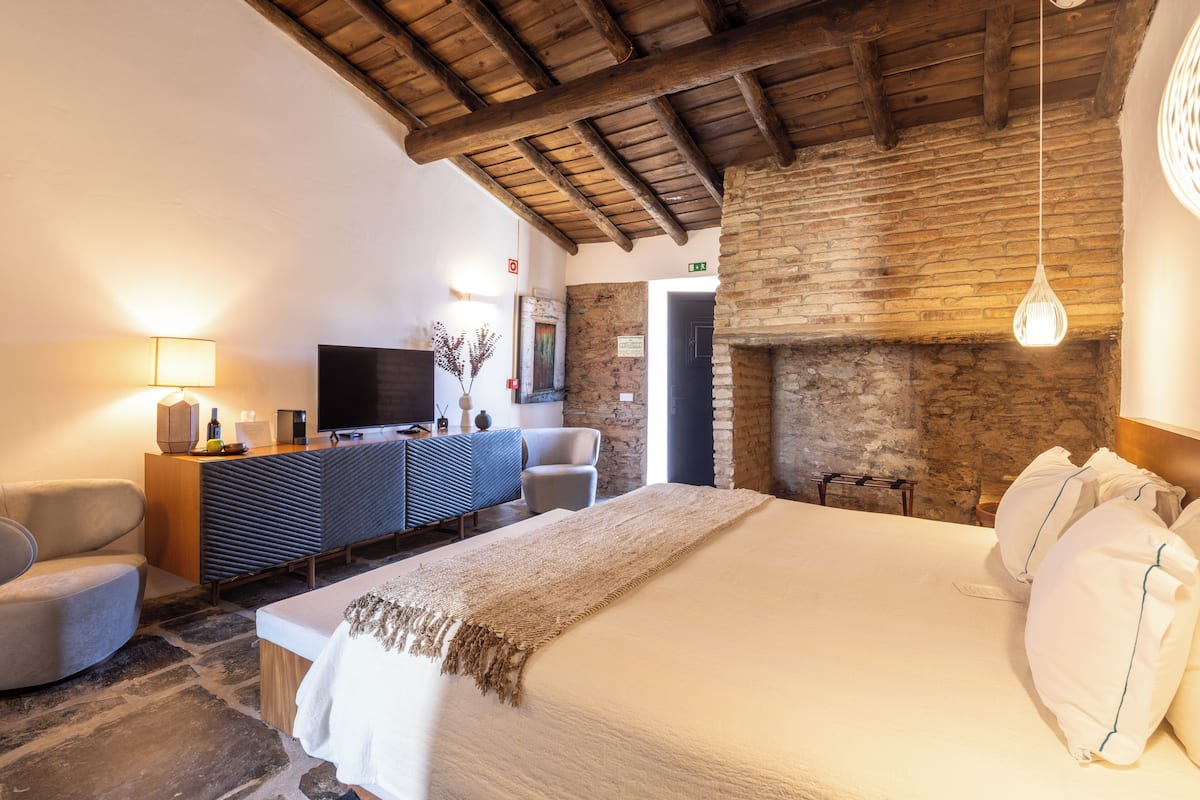 Een hotelkamer met een bed, een televisie, een bureau en een open haard.