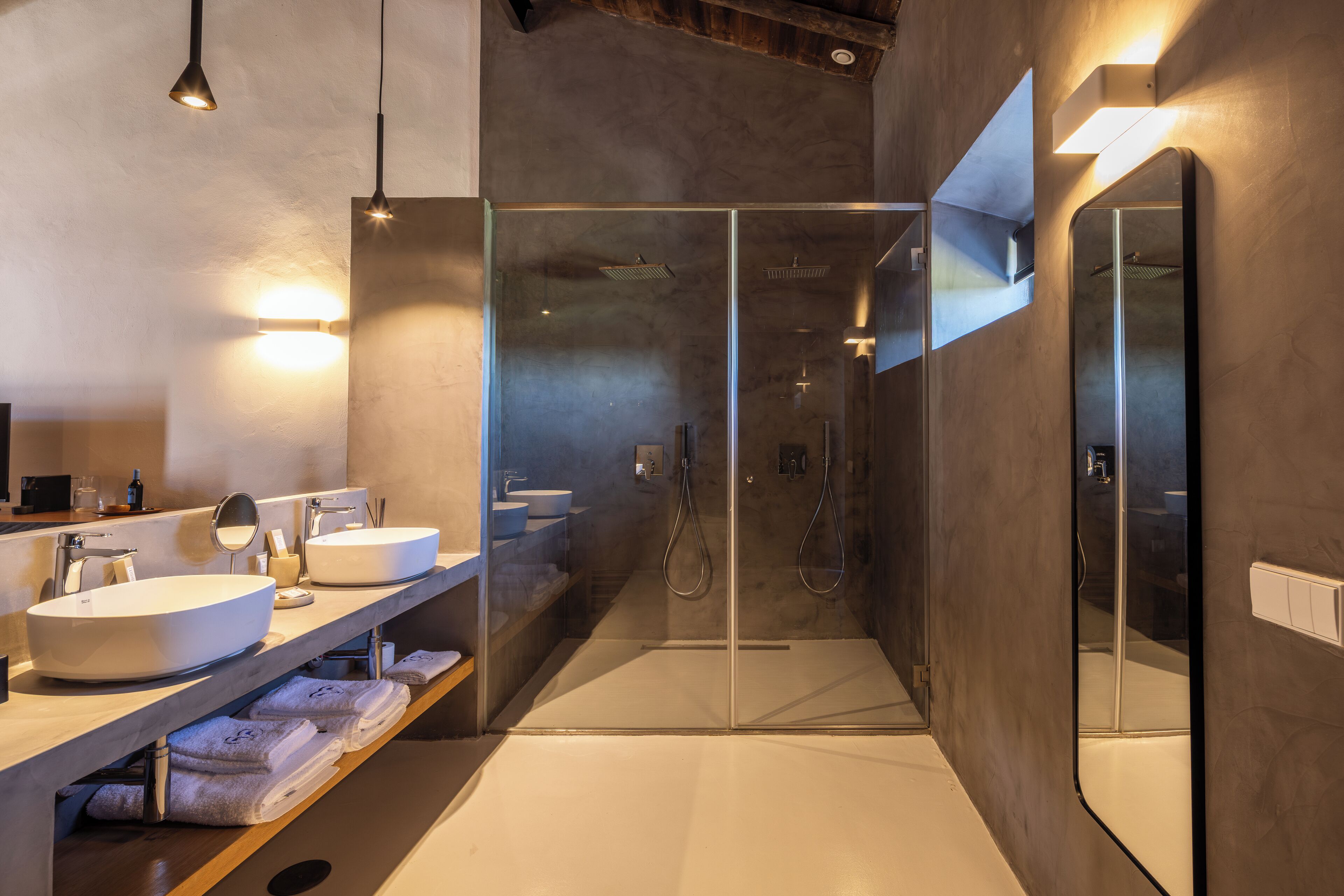 Un baño moderno con ducha de vidrio, un espejo grande y tocador con lavabo.
