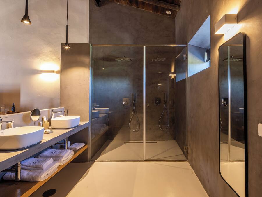 Un baño moderno con ducha de vidrio, un espejo grande y tocador con lavabo.