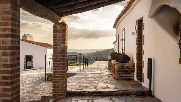 Un sendero de piedra que conduce a un edificio de fachada blanca y columnas de ladrillo.