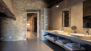 A modern bathroom with a stone wall, a large mirror, a sink, and a towel rack.