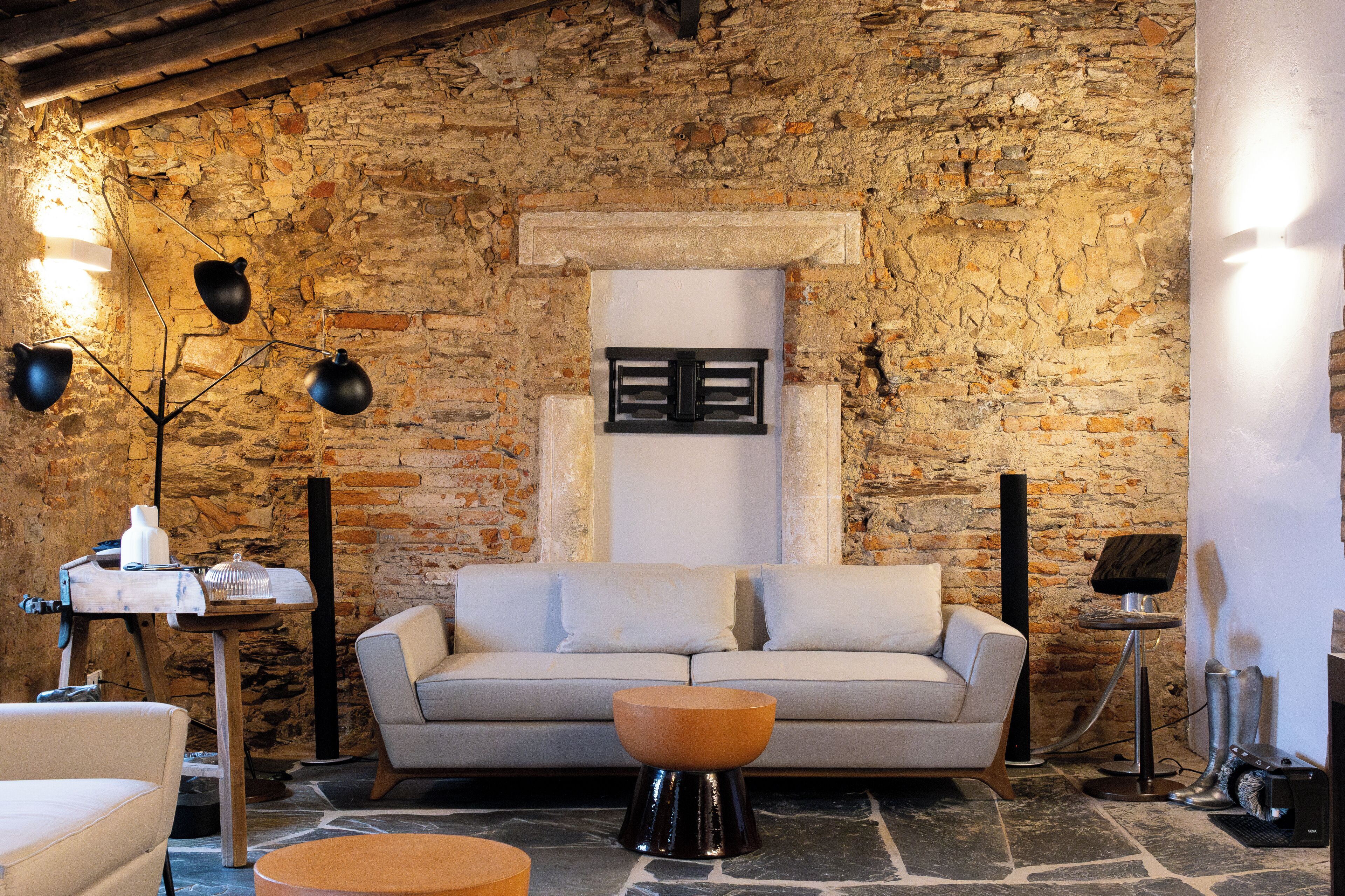 Una sala de estar acogedora con pared de piedra, un sofá, una mesa de centro y una lámpara.