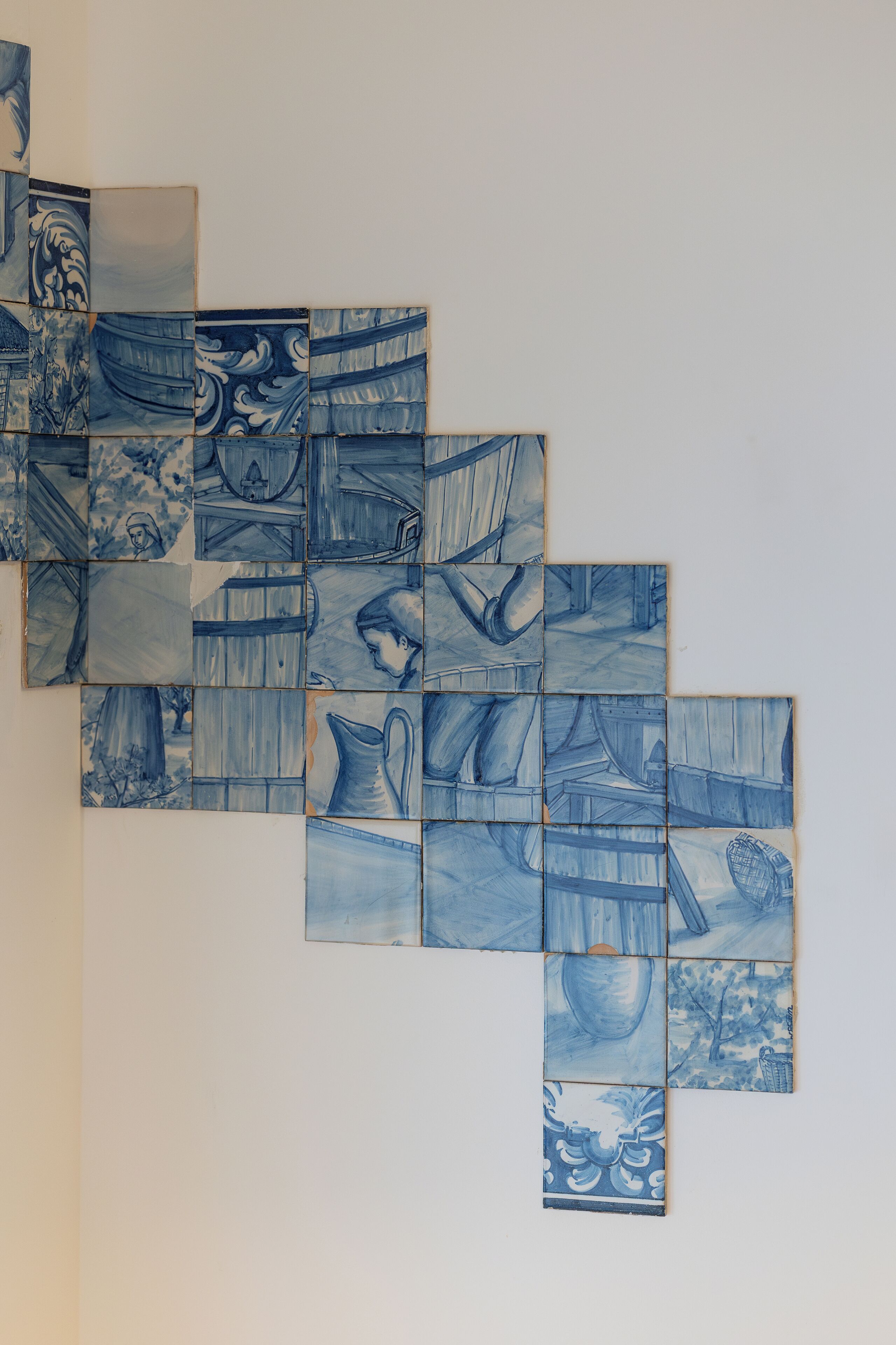 Un mur orné d’une mosaïque de carreaux de céramique bleus représentant différentes scènes.
