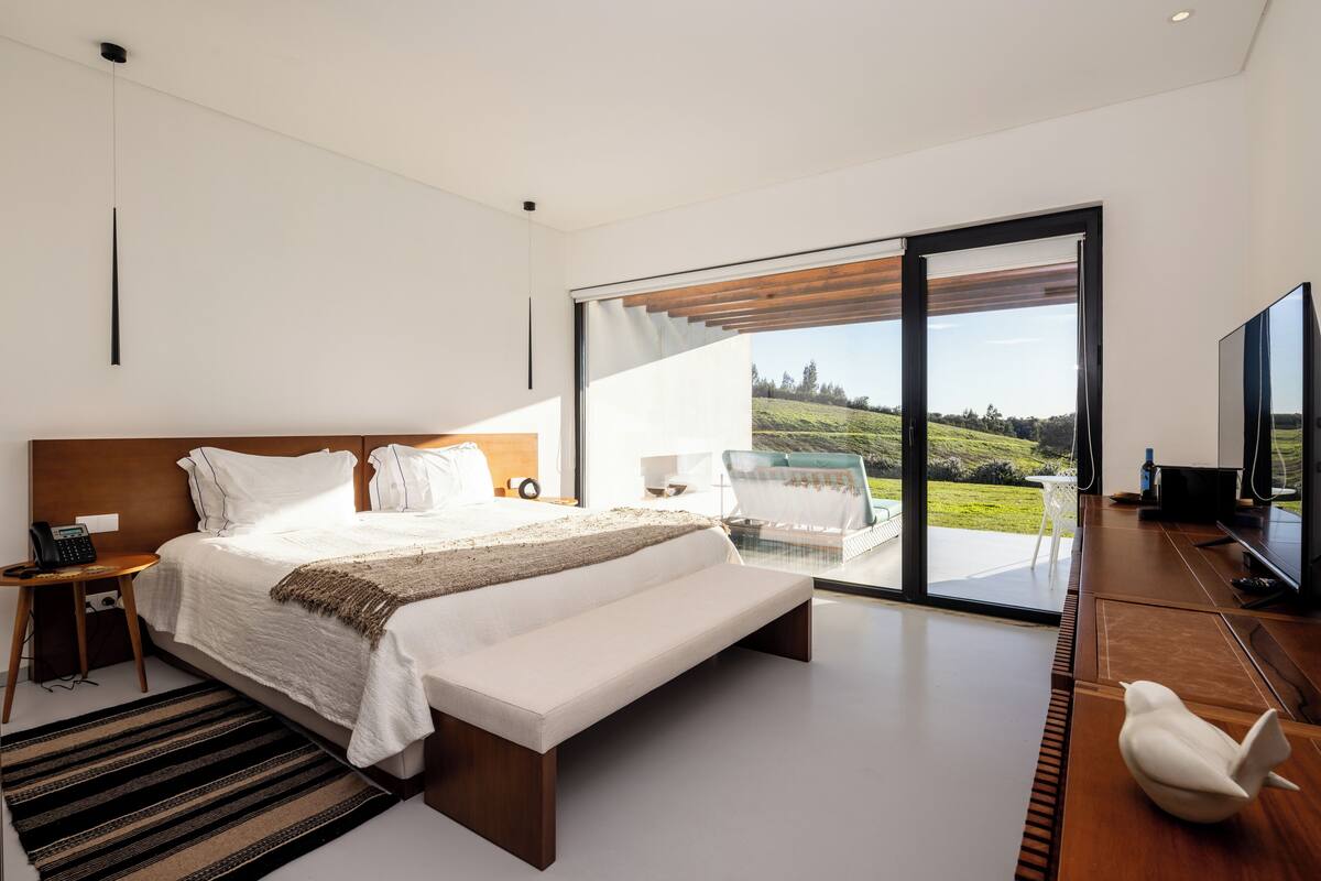 Een moderne slaapkamer met een groot bed, een televisie en uitzicht op het omliggende landschap.