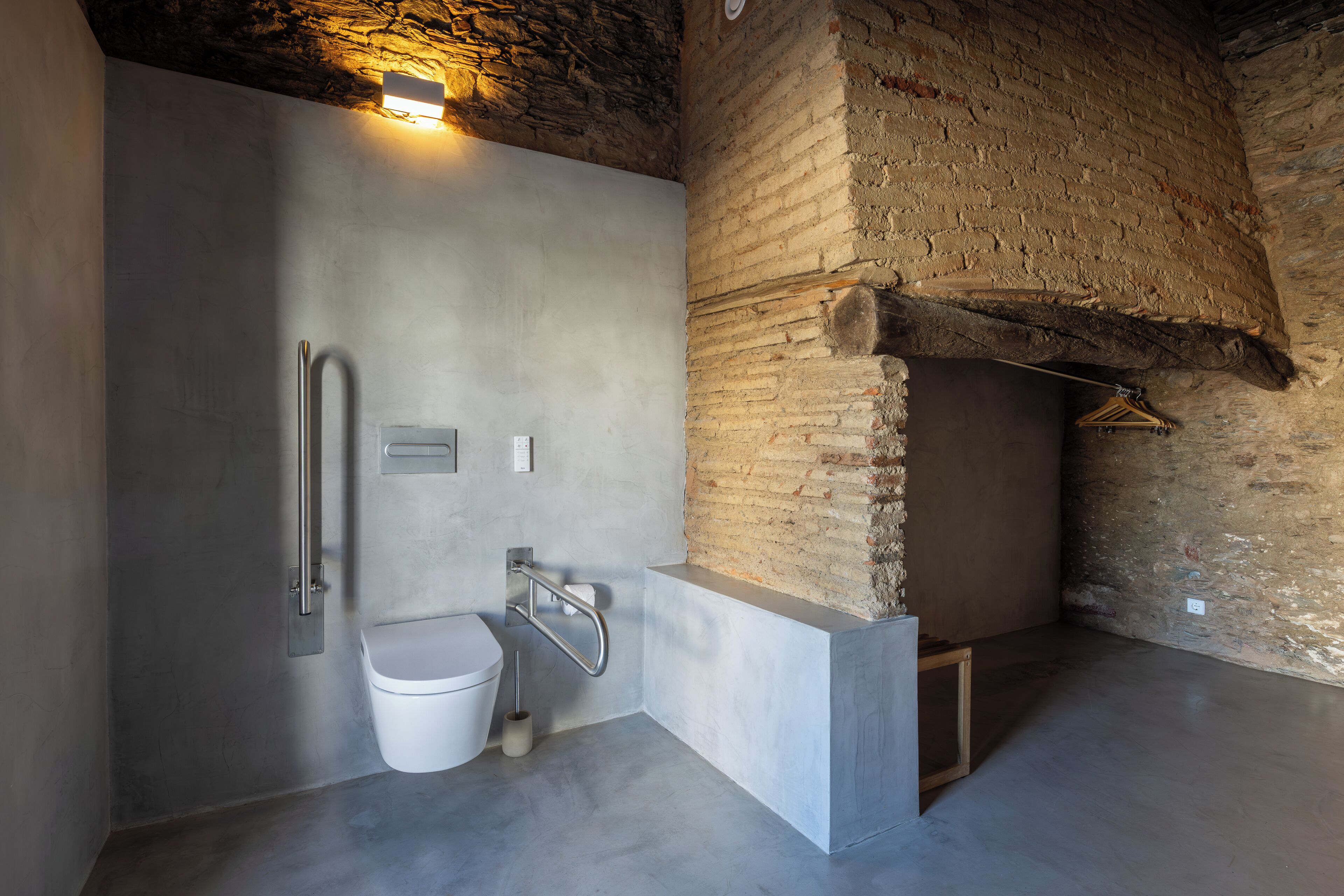 A modern bathroom with a concrete sink, a toilet, and a shower area.