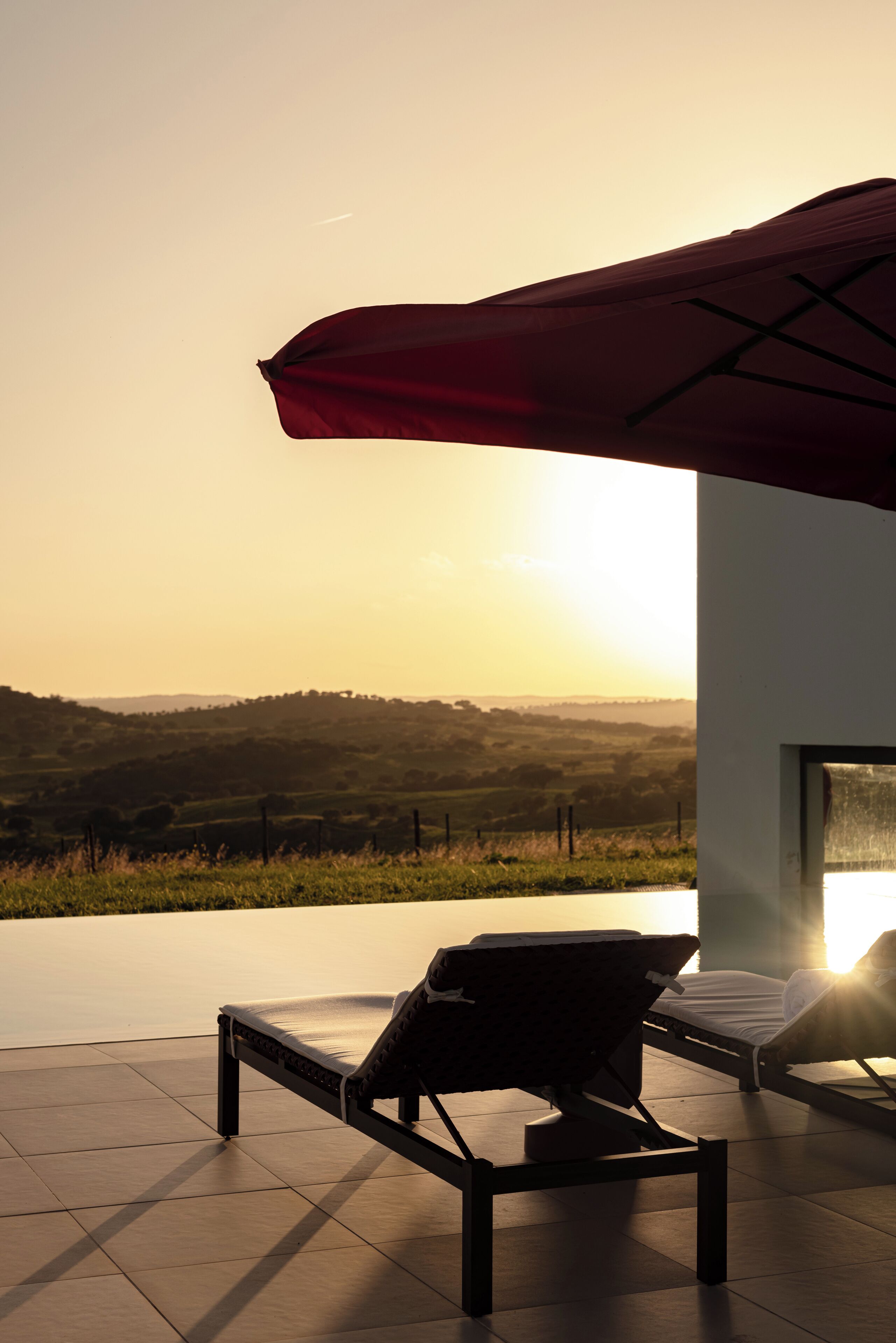 A modern outdoor seating area with a view of rolling hills during sunset.