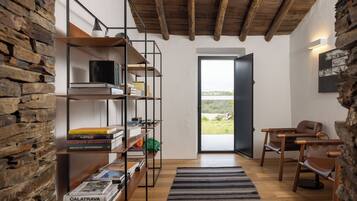 Een modern interieur met een houten boekenkast, lederen fauteuils en een uitzicht door een deur.