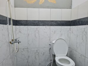A bathroom with a toilet, a shower, and marble tiles.