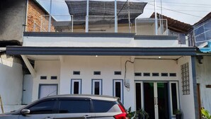 A two-story building with a car parked in front. - Omah Beji di Batu (Batu)