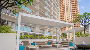 A rooftop lounge with outdoor seating, a water feature, and a view of adjacent high-rise buildings.