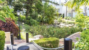 A wooden deck leading to a garden with a variety of plants and a small water feature. - Housing White Pearl Beach by Sharing Co (Marbella)