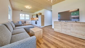 Una sala de estar moderna con un sofá modular, una mesa de centro de madera y un televisor sobre un mueble de madera.