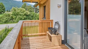Una terraza de madera con una parrilla y una puerta corrediza de vidrio.