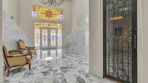 A grand lobby with marble flooring, ornate chairs, stained glass windows, and a decorative iron door. - 15,000 sqft Mansion 5 min from strip! 1.5 acre compound.  (Las Vegas)