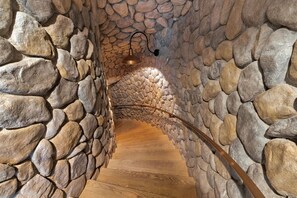 A stone-walled corridor with a wooden floor and a metal railing. - 15,000 sqft Mansion 5 min from strip! 1.5 acre compound.  (Las Vegas)