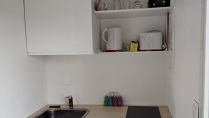 Une cuisine compacte équipée d’un évier, d’un lave-vaisselle et d’un plan de travail sur lequel se trouvent une planche à découper et une tasse.