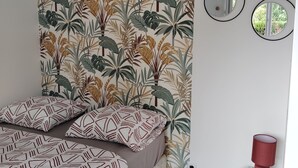 Une chambre à coucher avec un lit, un miroir rond et une petite table sur laquelle se trouve une lampe rouge.