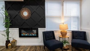 A living room with a fireplace, two chairs, a lamp, and a decorative wall piece. - Historic Fountain Sq in DT Indy (Indianapolis)