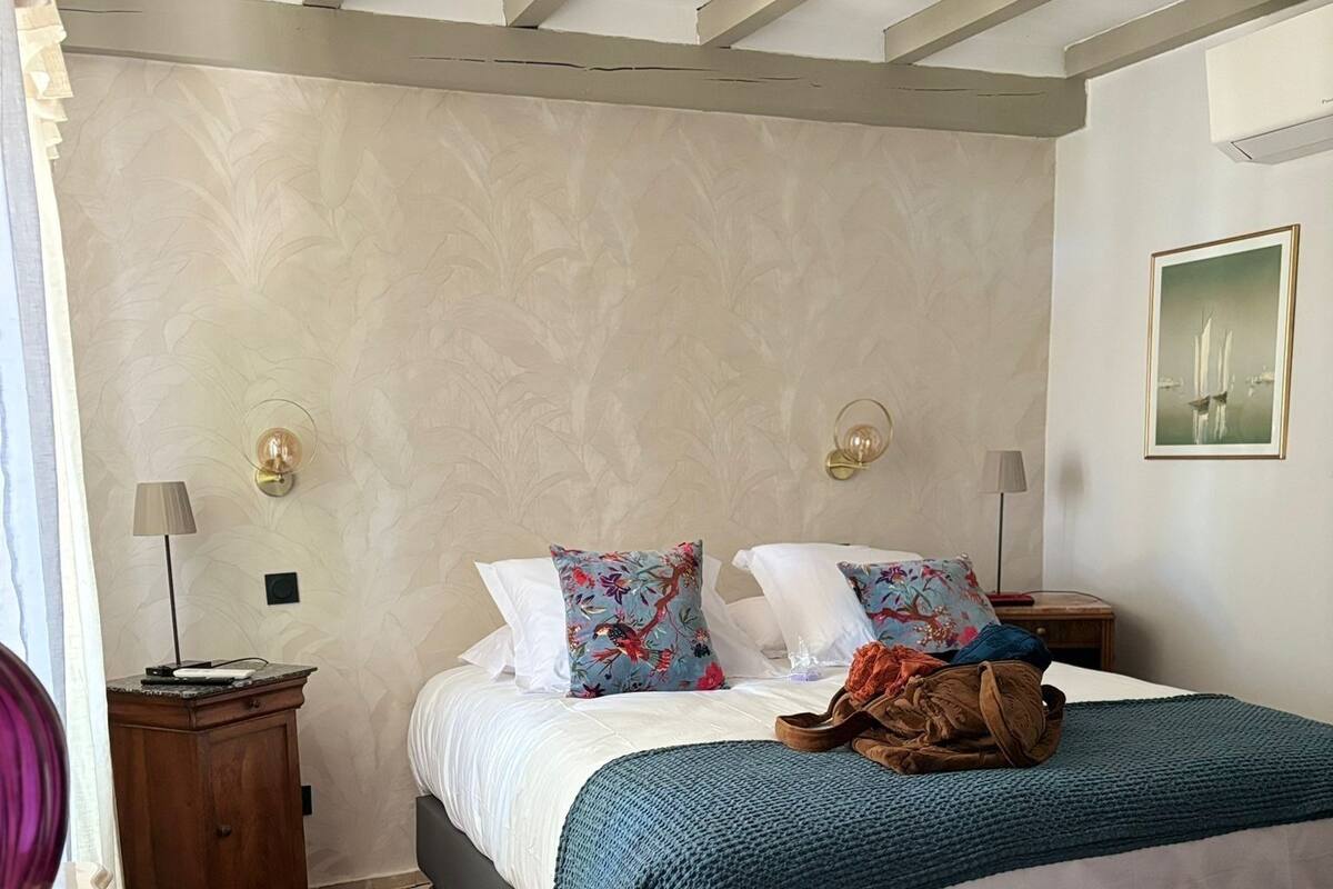 A bedroom with a bed, two nightstands, a chair, and a wardrobe.