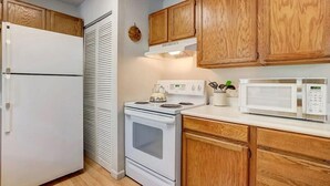 Una cocina con armarios de madera, un refrigerador blanco, una estufa y un microondas.