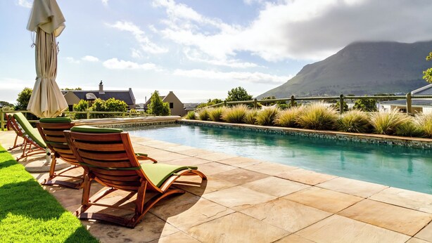 A poolside area with lounge chairs and a pergola. - Thatched Apartment with great views, full kitchen, Wifi in Noordhoek, Cape Town (Cape Town)