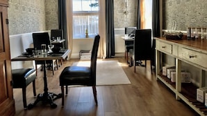 A dining area with a table set for two, a black leather chair, and a white cabinet with boxes. - No22 (Barnstaple)