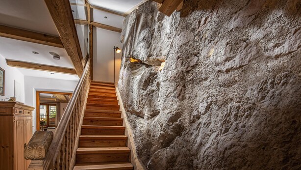 A staircase with wooden steps and a stone wall.