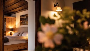 A cozy bedroom with a wooden ceiling, a bed with a checkered duvet, and a wall-mounted lamp.