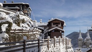 A snow-covered mountain village with traditional wooden buildings, a church, and a ski lift.