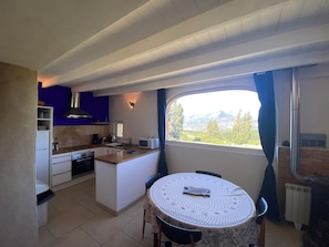 Une cuisine compacte avec un coin repas, une fenêtre donnant sur les montagnes et une cuisinière encastrée.