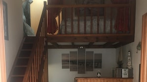 A living room with a wooden staircase, a brown sofa, a small table, and a decorative floor pattern.