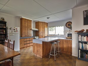 A kitchen with a central island, wooden cabinets, a white refrigerator, and a dining area with chairs.