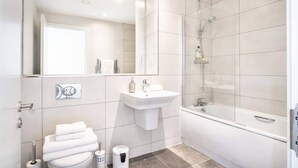 Un baño moderno con inodoro, lavamanos y ducha.