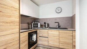 Una cocina moderna con armarios de madera, un microondas, un hervidor y un reloj en la pared.