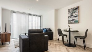 Ein modernes Wohnzimmer mit einer Couch, einem Esstisch mit Stühlen und einem Bild an der Wand.